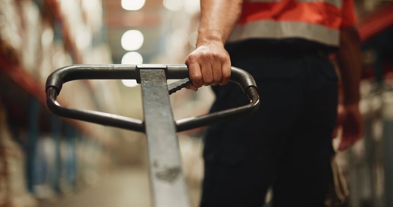 Handle, trolley and hand of worker in warehouse for distribution, cargo or quality assurance. Logistics, freight and male supply chain manager with pallet jack for stock delivery in factory.