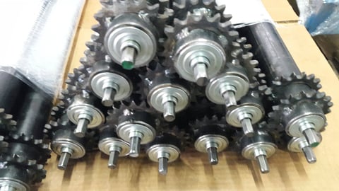 Collection of metal industrial gears and sprockets with bolts arranged on a wooden surface