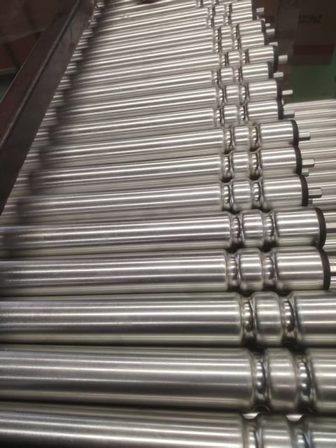 Multiple metallic cylindrical rollers aligned in rows with connecting chains for industrial conveyor system